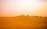 A smiling woman enjoying a desert safari at sunset with golden dunes in the background.