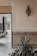 A beautifully decorated interior features a beige wall with intricate geometric tile patterns along the lower half and ornate white engravings around the doorway. There is a decorative wall lamp with an intricate design. In the foreground, lush green plants add a natural touch to the setting.