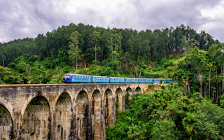 A blue train crossing the Nine Arches Bridge in Ella, Sri Lanka
