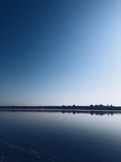 A serene landscape of clear blue water reflecting the sky.