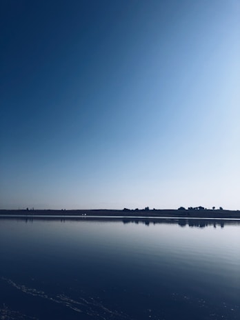 A serene landscape of clear blue water reflecting the sky.