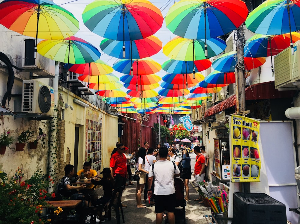 people gathering under multicolored street umbrellas