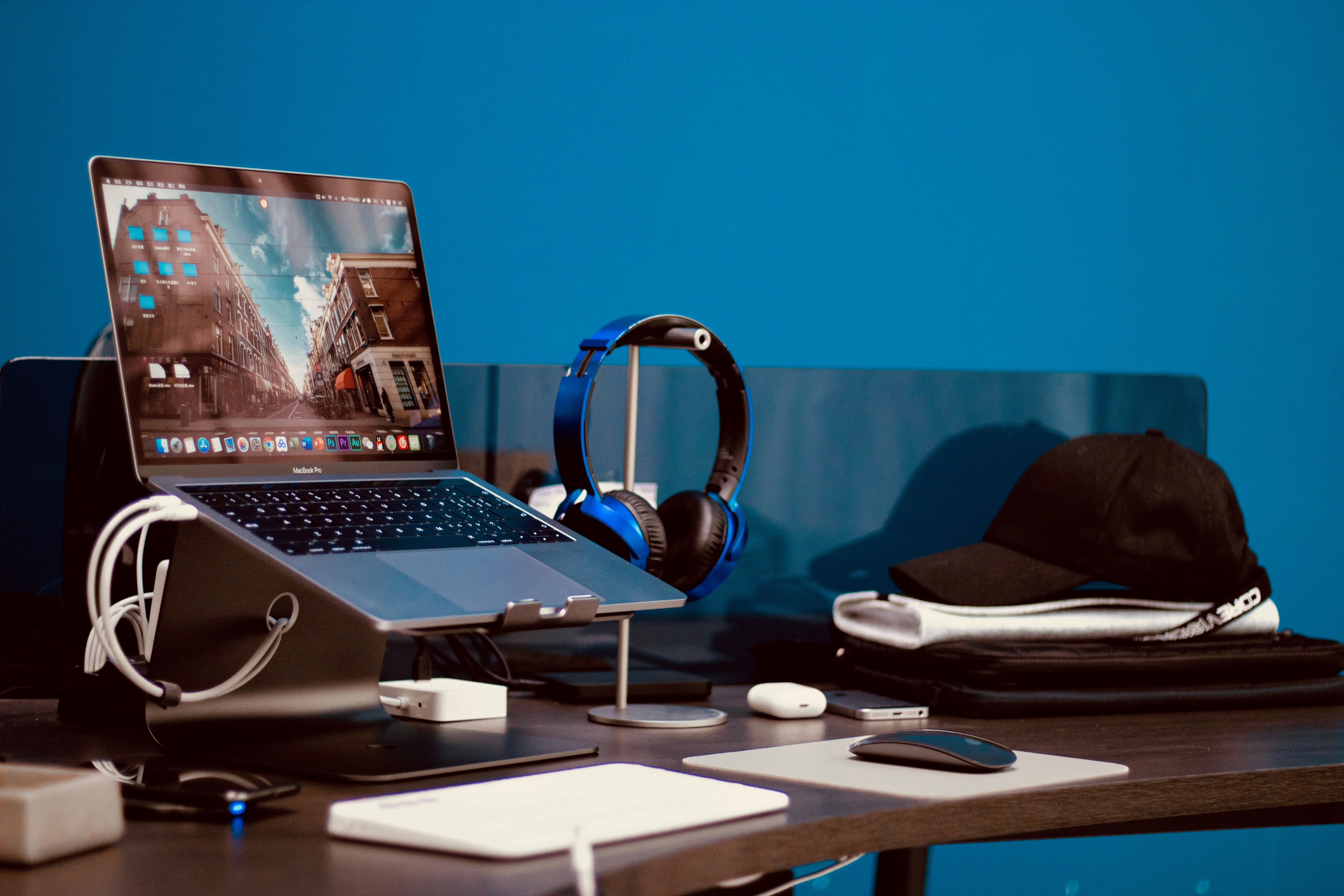 turned-on laptop beside headphones and cap on desk