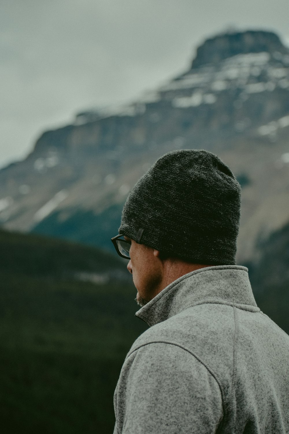 man wears gray knit cap and eyeglasses at the hill