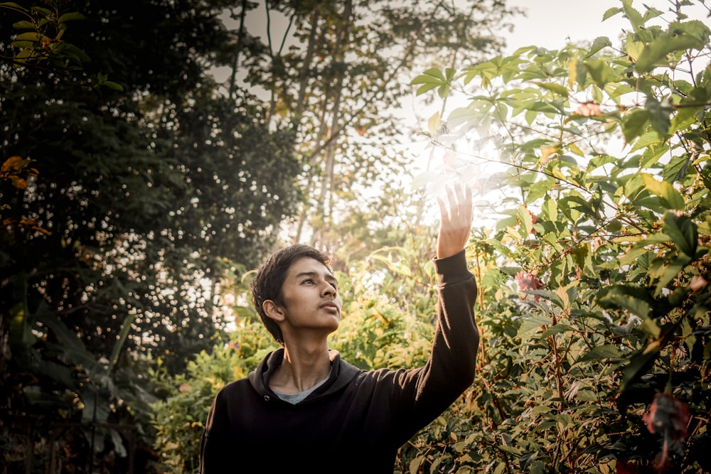 man reaching for green leaf