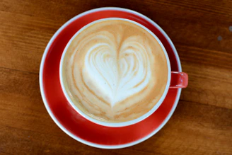 Warm-toned photo of a barista latte art heart in a cozy café setting.