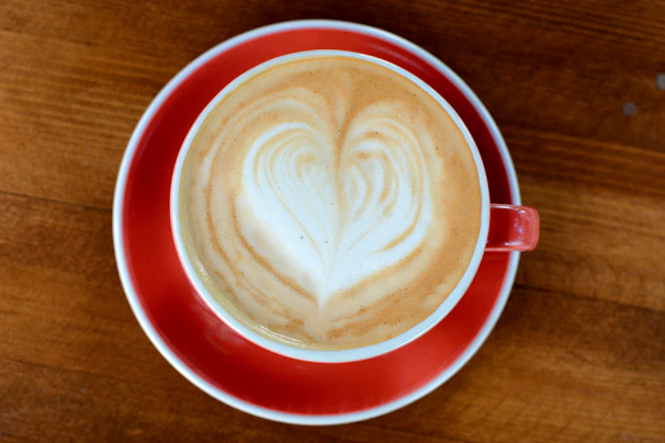 Warm-toned photo of a barista latte art heart in a cozy café setting.