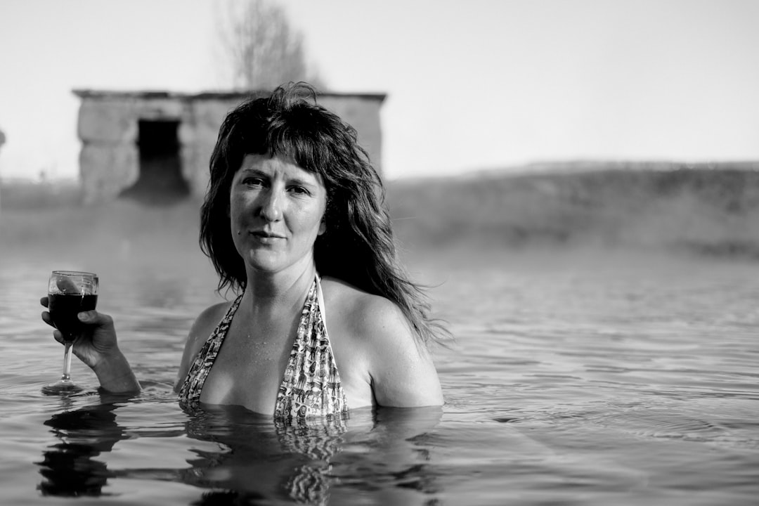 grayscale photography of woman underwater holding wine