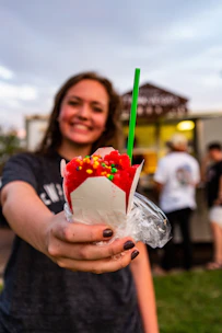 Close-up of colorful tropical shaved ice with fresh fruit toppings in a festive cup.