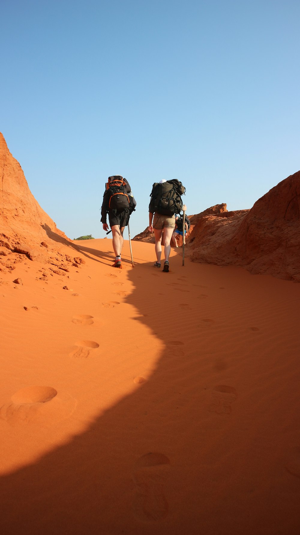 two person hiking on desert during daytime