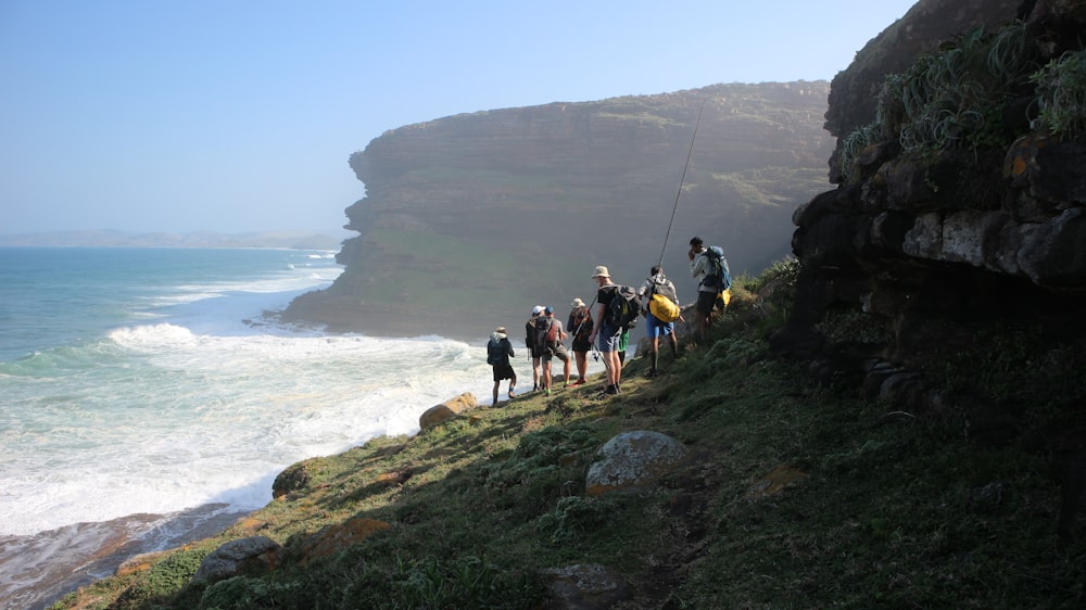 people hiking on grass mountain seashore