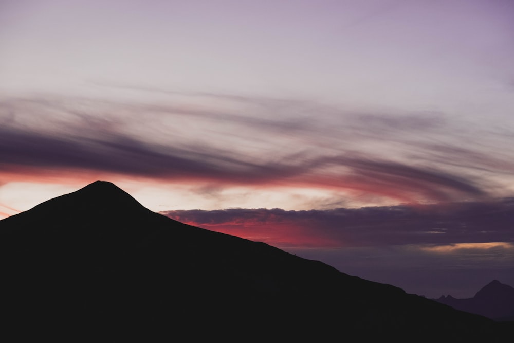 a silhouette of a mountain against a cloudy sky