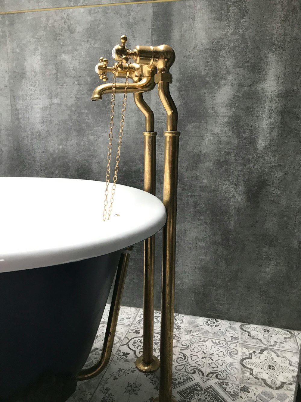 brass faucet near white and black bathtub