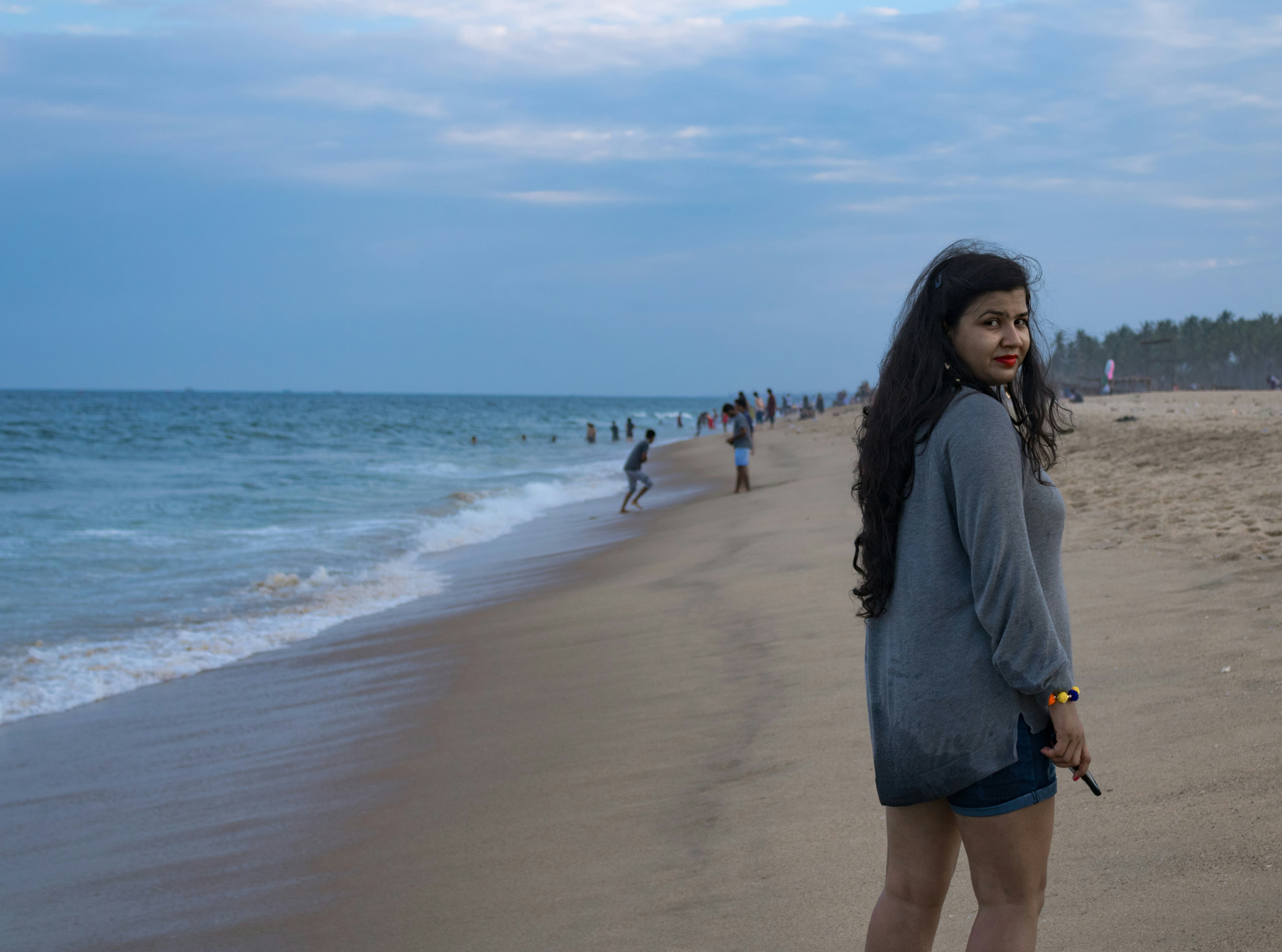 woman wearing grey long-sleeved shirt standing on seashore