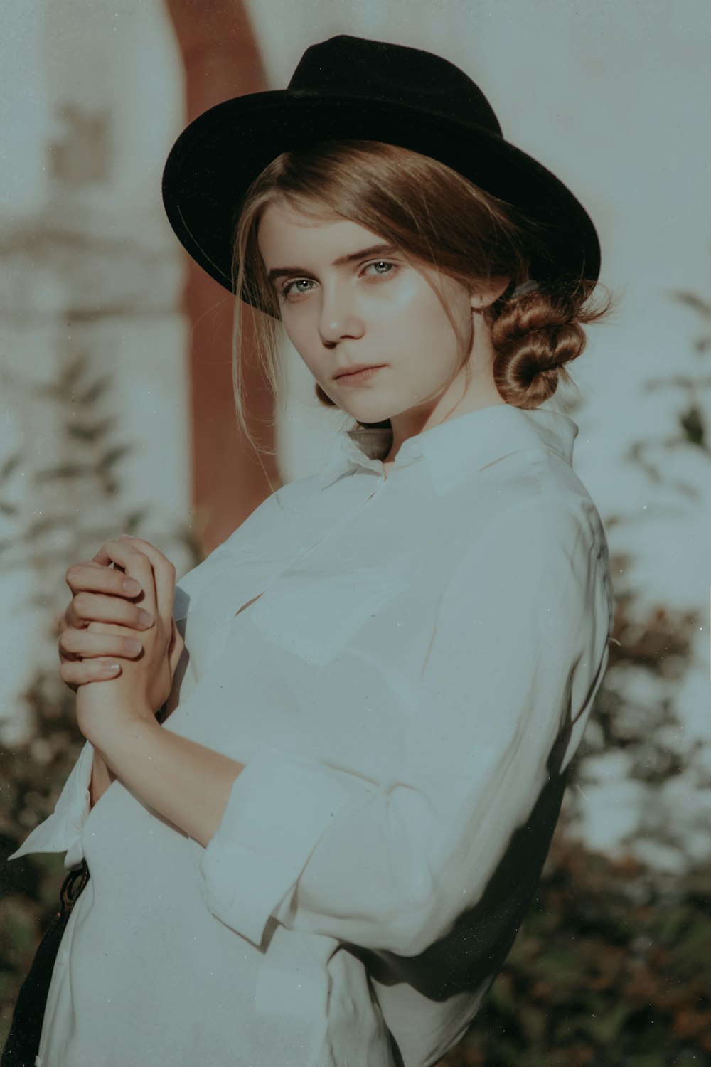 흰 칼라 버튼 업 긴팔 셔츠와 검은 모자를 쓰고 서 있는 여자