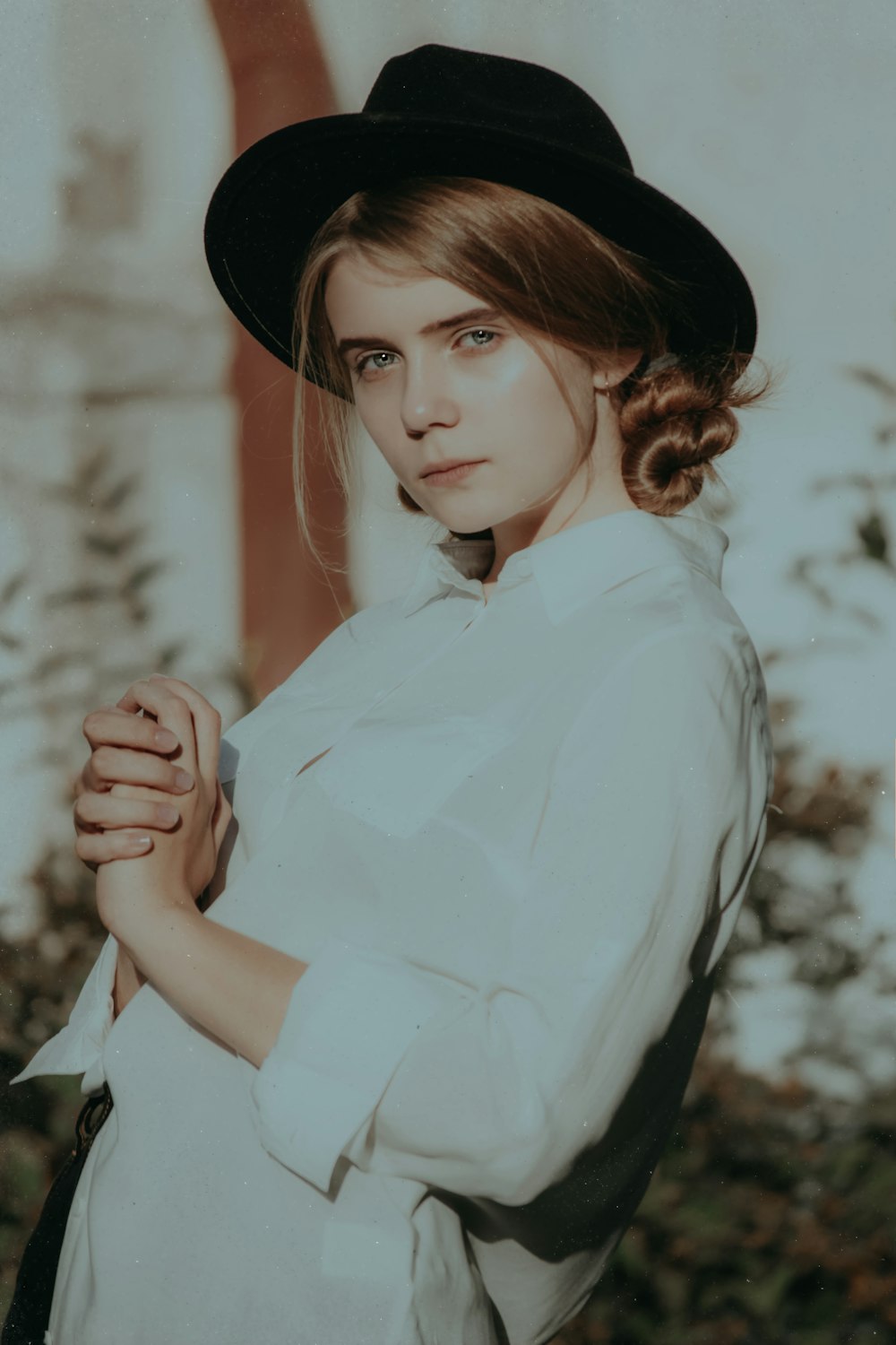 woman wearing white collared button-up long-sleeved shirt and black hat standing