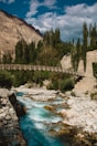 a river flowing under a bridge surrounded by mountains
