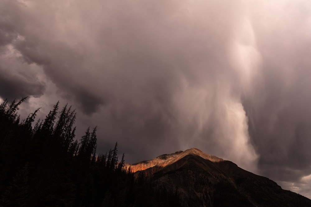 brown mountain under cloudy sky