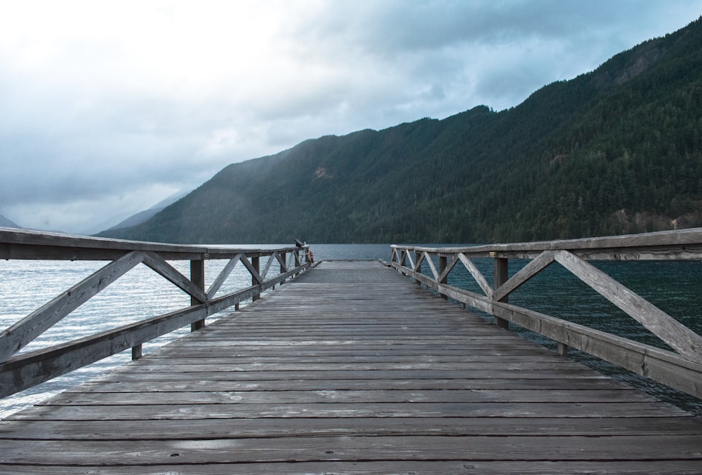 gray wooden dock near mountain during daytime