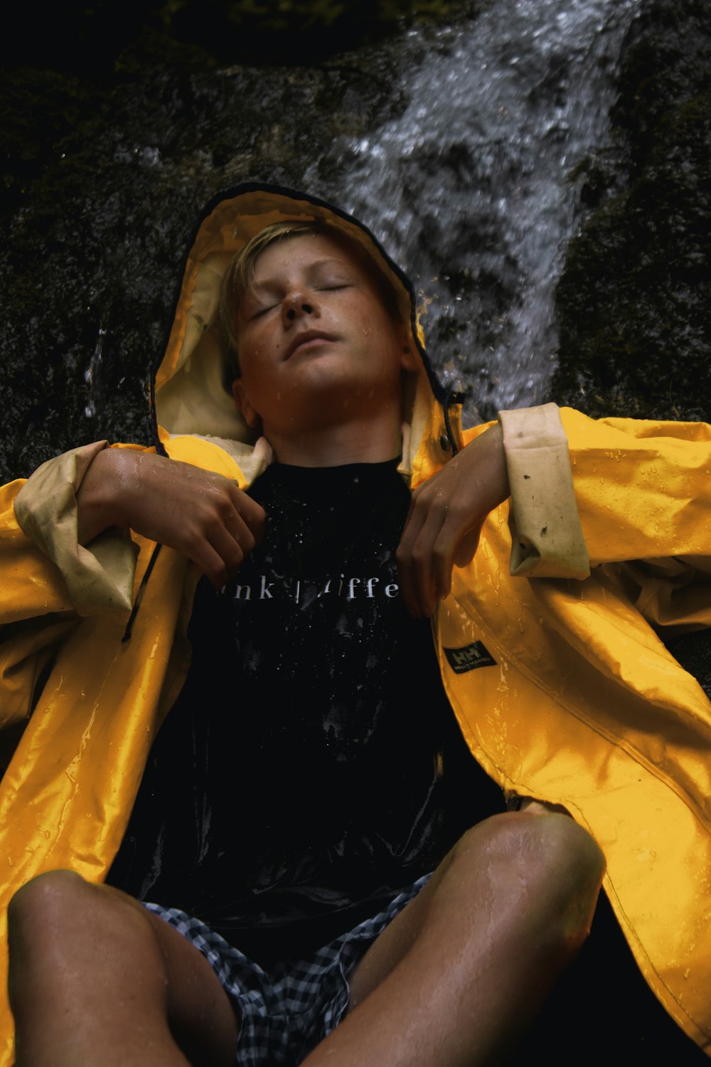 man sitting down under a flowing waterfall