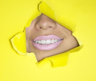 ripped yellow paper showing woman's nose and lips