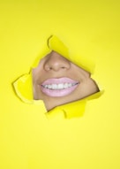 ripped yellow paper showing woman's nose and lips
