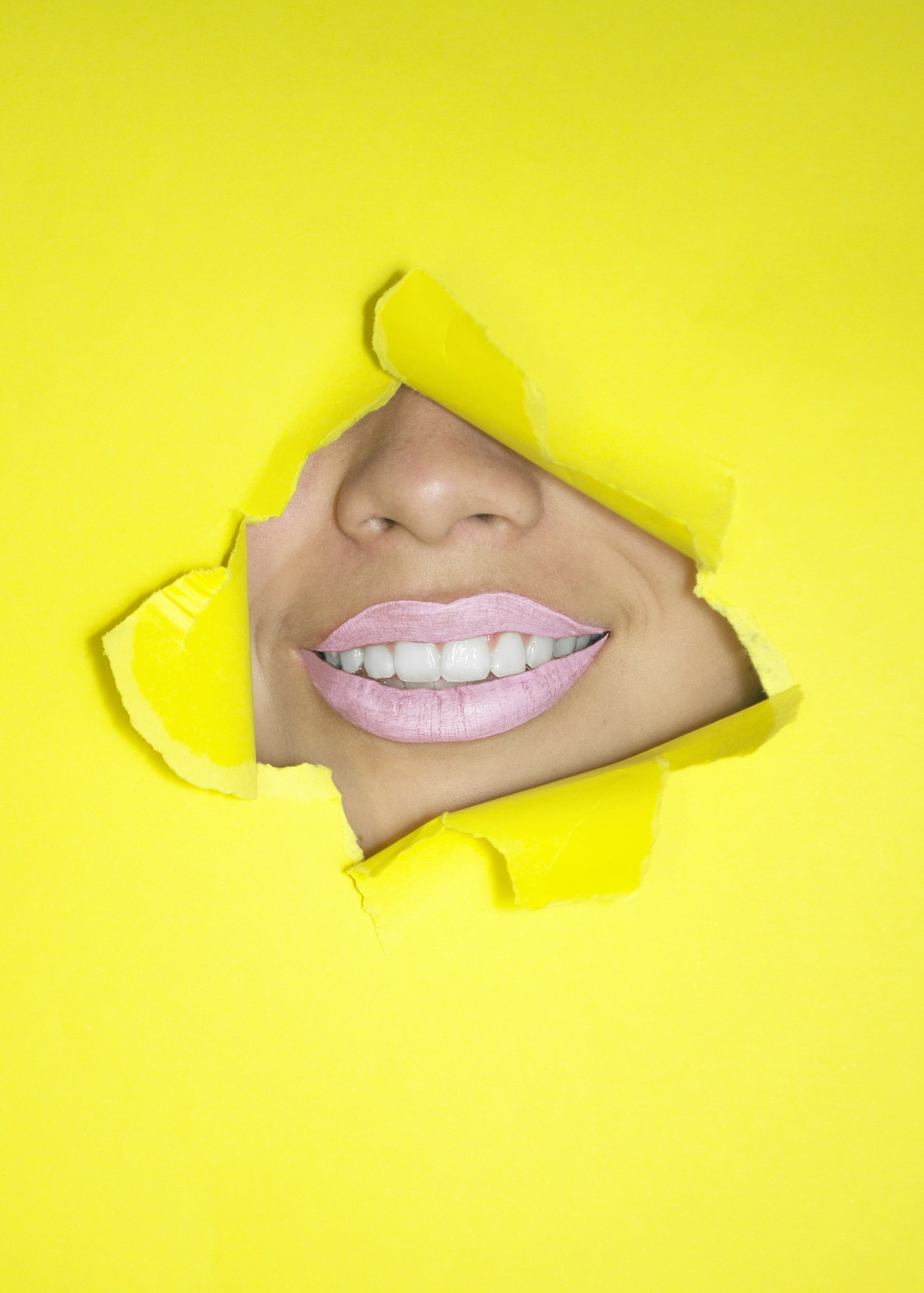 ripped yellow paper showing woman's nose and lips