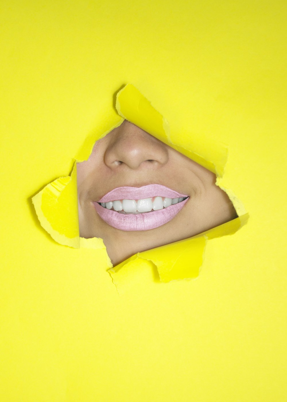 ripped yellow paper showing woman's nose and lips