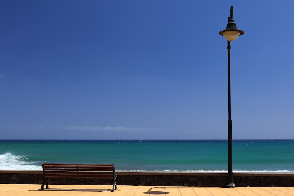 black street lamp near brown wooden waiting bench