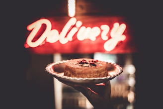 A delivery person handing over a cake box to a happy customer at their home.