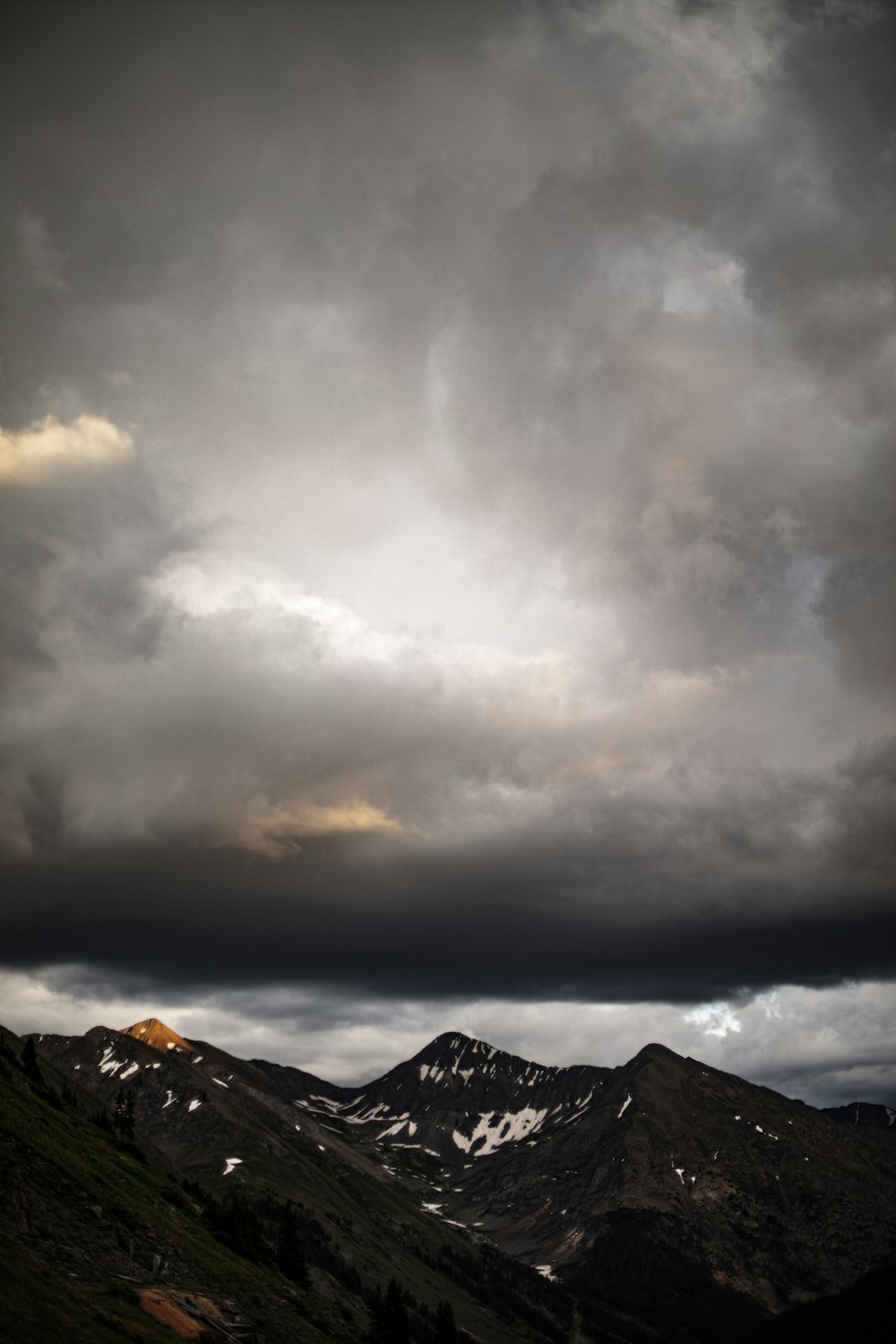 a mountain range under a cloudy sky with mountains in the background