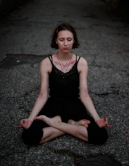 A calm person sitting cross-legged outdoors, eyes closed, deeply connected with their body.