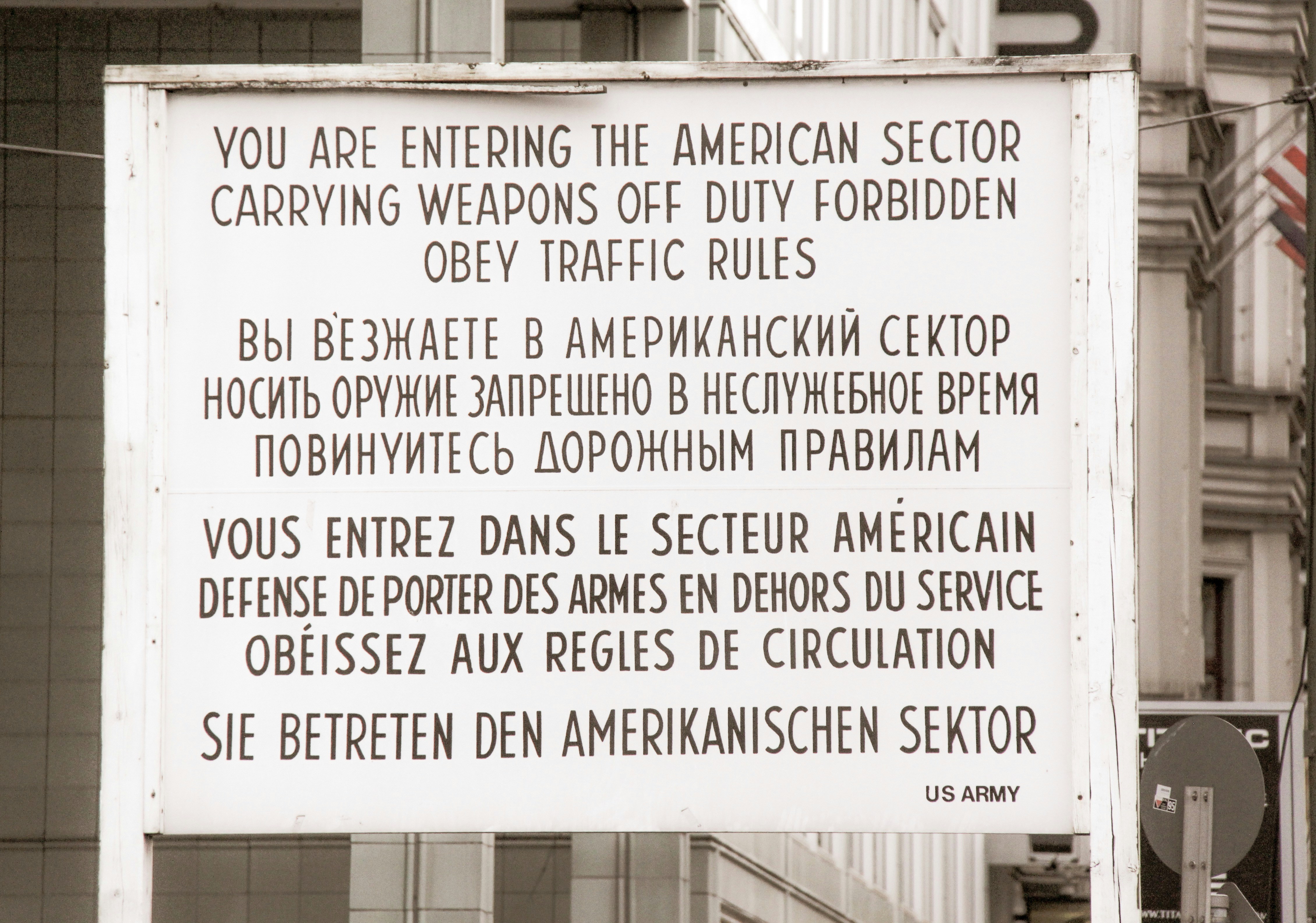 a sign on the side of a building that says you are entering the american sector, At Checkpoint Charly in Berlin history has left their signs.