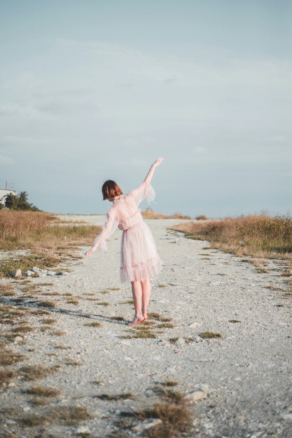 woman wearing white long-sleeved dress standing on road during daytime