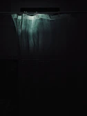 A shower liner gently swaying with steam rising in a warmly lit bathroom.