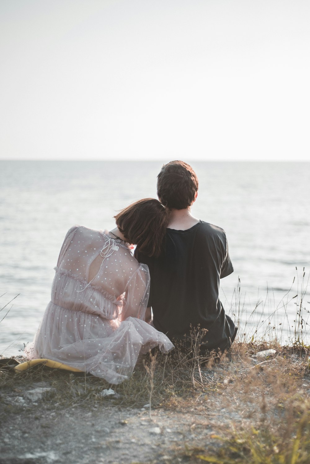 man and woman sitting in front of body of water during daytime