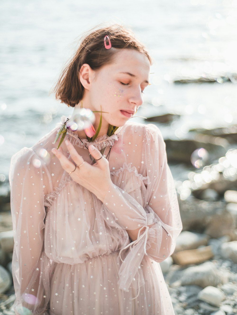 girl wearing white long-sleeved dress standing in beach during daytime