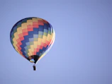 A vibrant hot air balloon preparing for takeoff with a clear blue sky background
