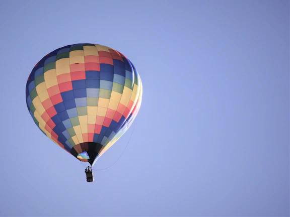 A vibrant hot air balloon preparing for takeoff with a clear blue sky background