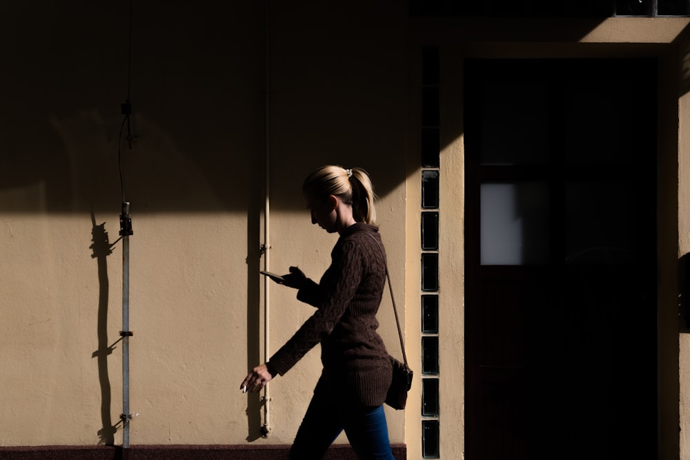 woman walking while holding black Android smartphone