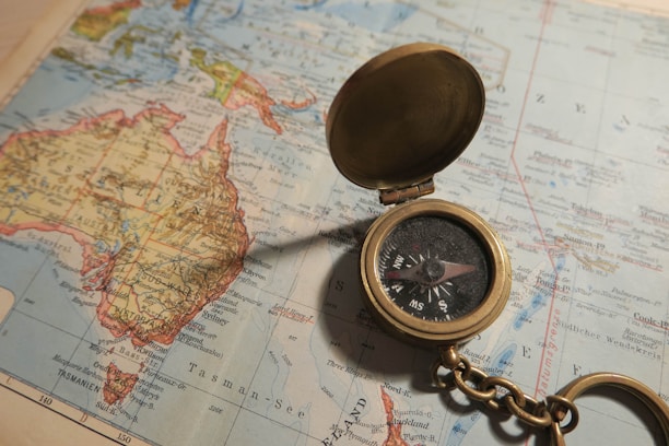 A vintage brass compass resting on an old world map, softly lit to highlight its details.