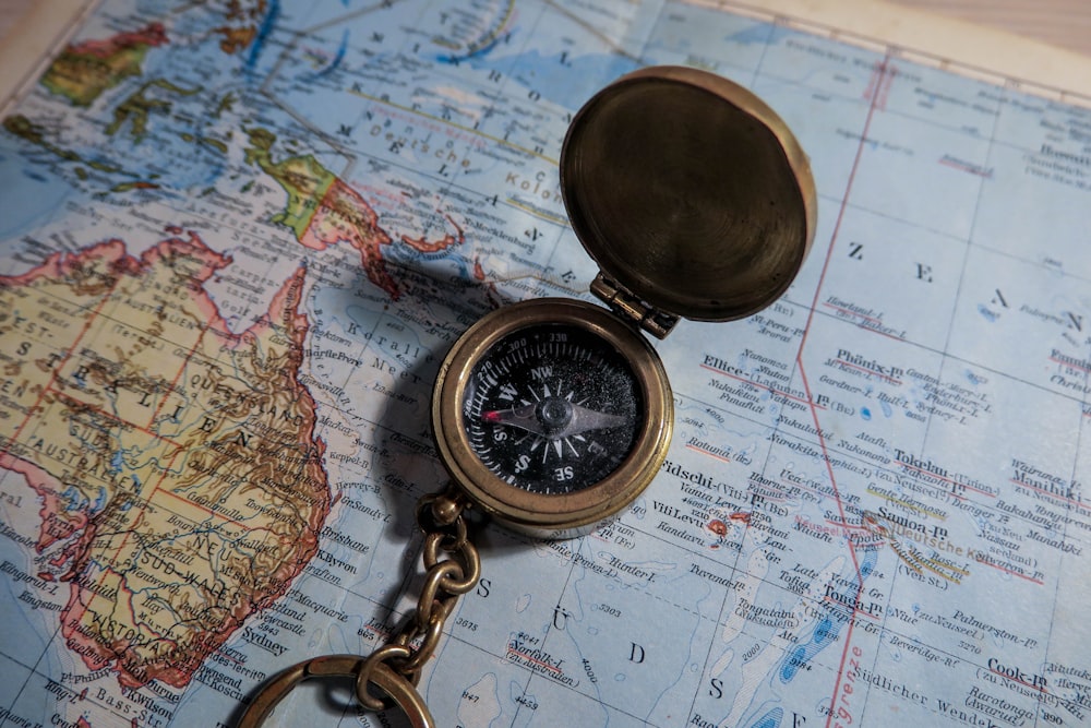 round brass-colored compass on map