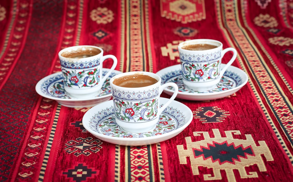 three multicolored floral ceramic cups and saucers