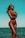A woman stands confidently at the beach, wearing a red bikini and sunglasses. The ocean and sky create a serene backdrop, and her arms are crossed around her chest, conveying a feeling of relaxation and empowerment.
