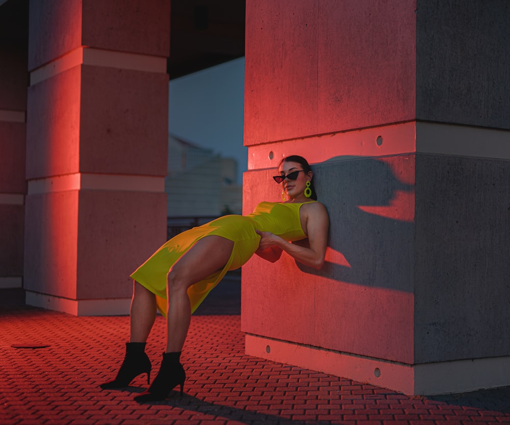 woman in ellow slit dress leaning back on wall