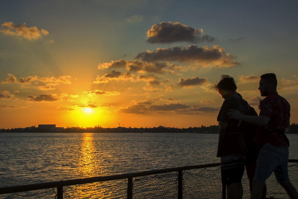 silhouette of two person beside railings