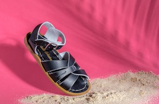 Close-up of a traditional Arabic sandal with intricate leatherwork, set against a warm desert background.