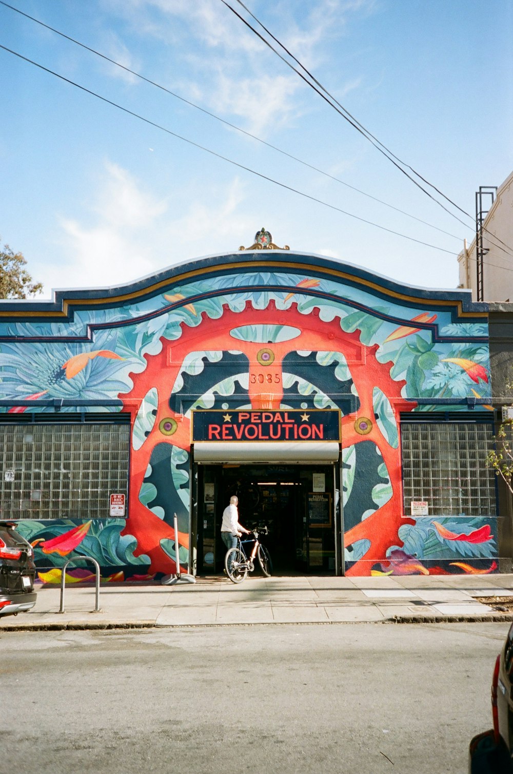 man standing near bike beside Pedal Revolution store under blue and white skies during daytime