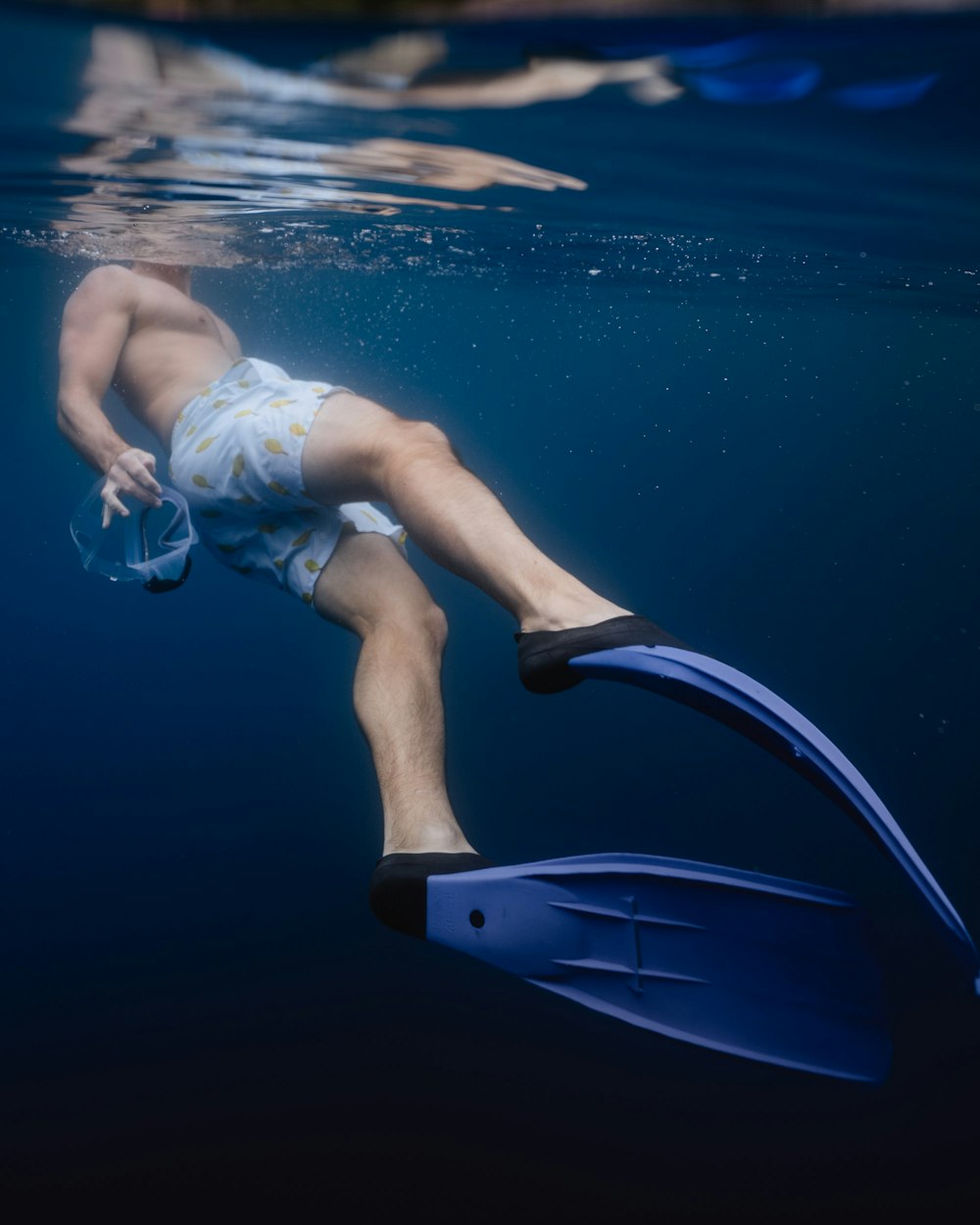 under water photography of man wearing blue flippers