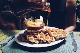 person poring syrup on waffles